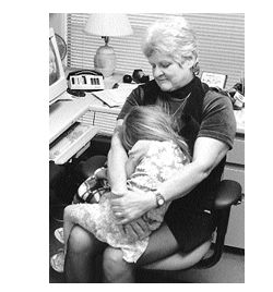 Social worker holding a sleeping child in her lap looking very concerned