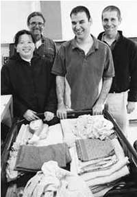 Two Arc workers in background with Tuyet and Hector in front of a cart with the laundrey they juts folded.