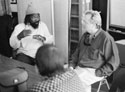 Wayne telling a story as in a group, Leland listens attentively
