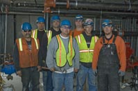 group of sprinkler fitters with pipes behind them