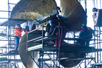Shipyard workers working on  a large propeller